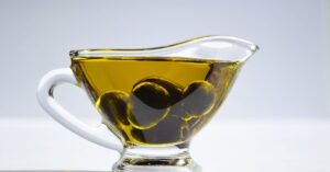 High-resolution image of a glass cup filled with olive oil and olives, ideal for culinary themes.