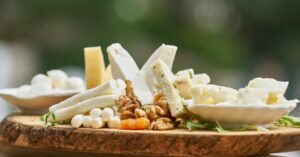 A delicious assortment of cheese and nuts on a rustic wooden board, perfect for appetizers.