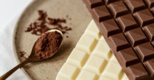 A delicious assortment of milk and white chocolate bars with cocoa powder on a plate. Perfect for confectionery enthusiasts.